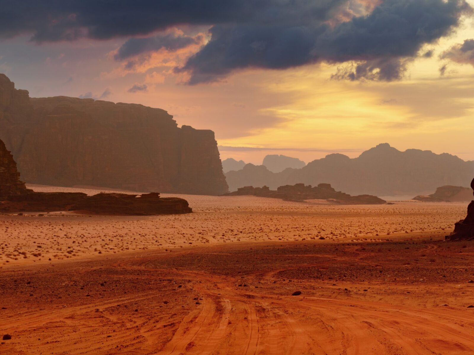 Sunset,Over,A,Desert,With,Rock,Formations,And,Scattered,Clouds.